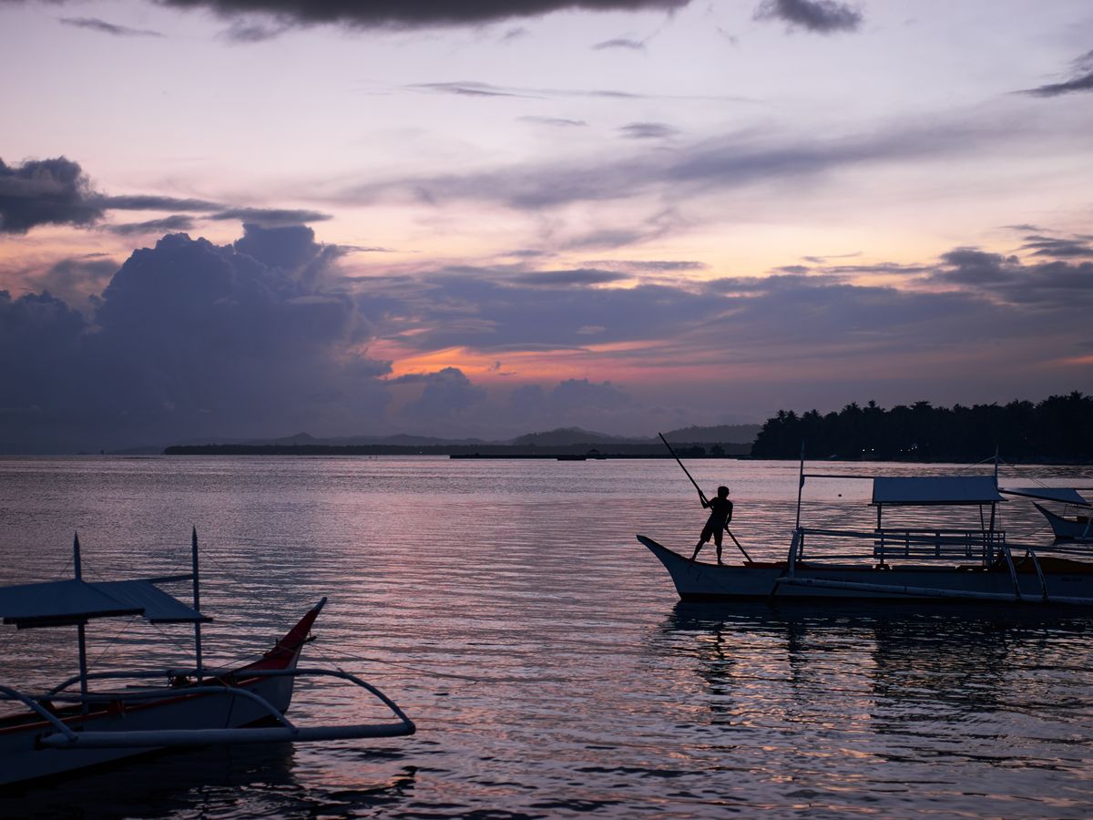 Fishing boats on calm water at sunset in the Philippines