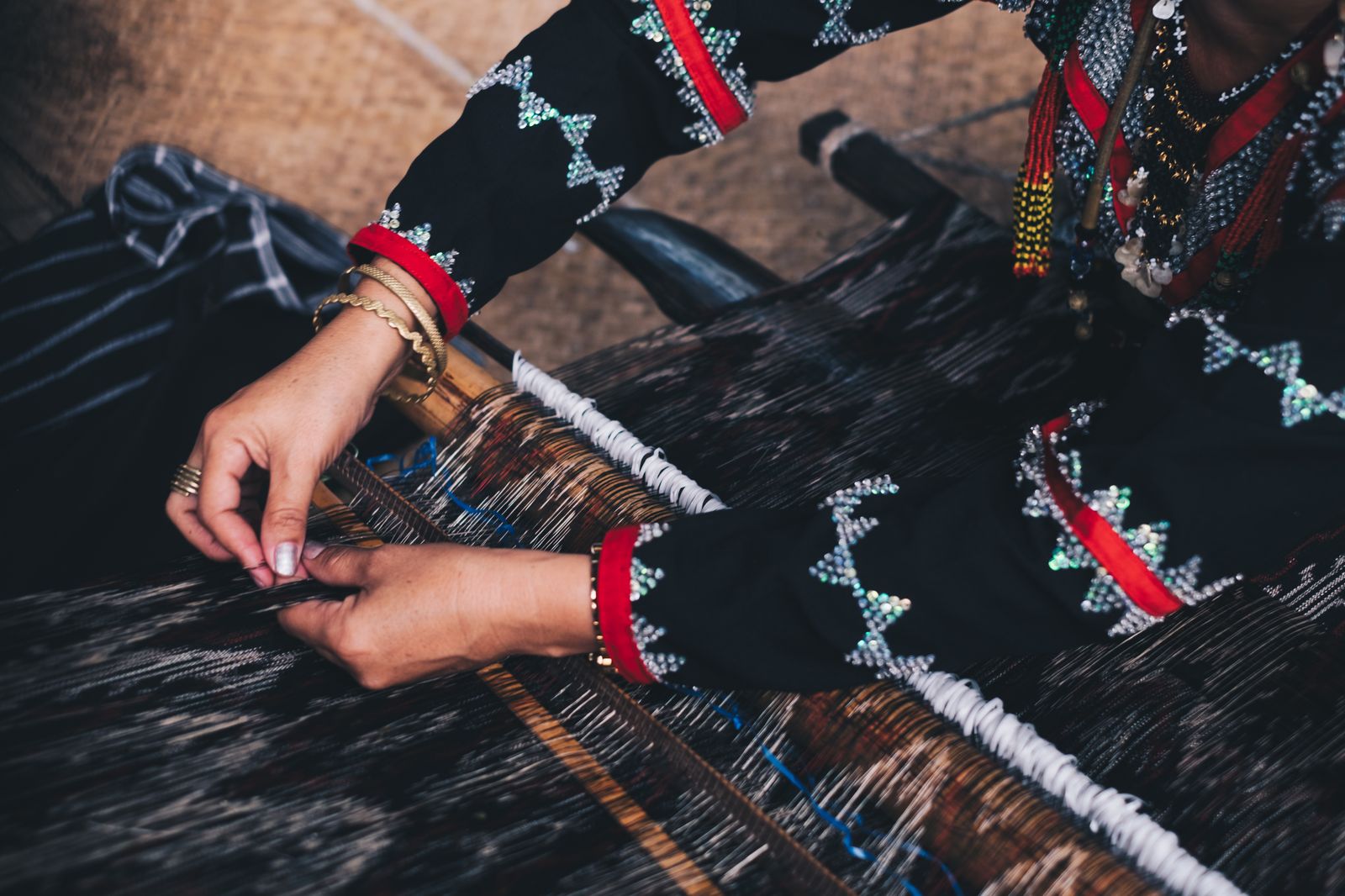 Hands weave naturally dyed t'nalak cloth on a traditional loom in the southern Philippines