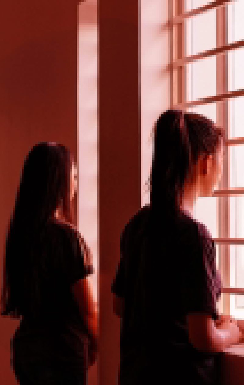 Two young people silhouetted against a lit window