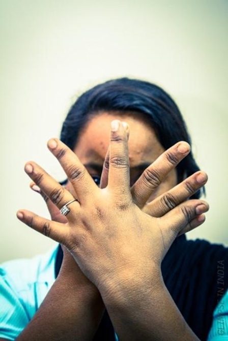A woman holds her hands crossed over her face
